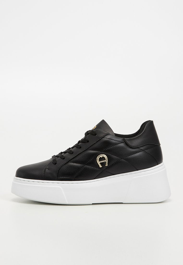 Schwarze Plattform-Sneaker aus glattem Leder, mit gesteppter Gestaltung, runder Zehenpartie, weißer Sohle und einem goldenen Akzent-Logo an der Seite.