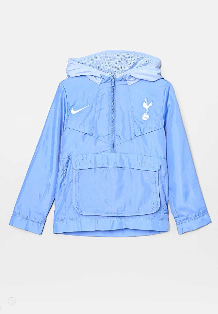 Hellblaue Nylonjacke mit Kapuze, halbem Reißverschluss, Klappentasche auf der Vorderseite, weißem Nike-Logo auf der linken Brust und Emblem von Tottenham Hotspur auf der rechten Brust.