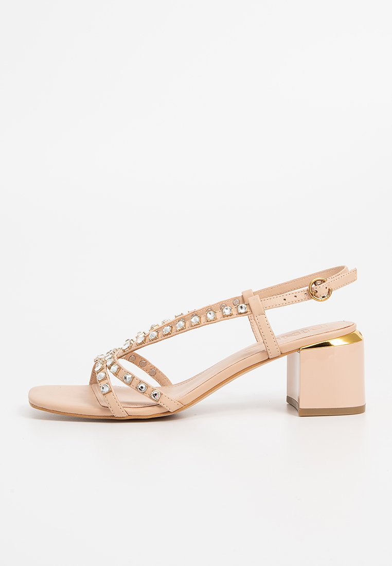 Beige Riemchensandalen mit einem kleinen Blockabsatz, verziert mit klaren Strasssteinen entlang der Riemen und einem goldenen Akzent am Absatz.