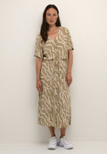 Beige, knielanges Kleid mit einem welligen weißen Muster, kurzen Ärmeln, Knopfleiste und verstellbarem Kordelzug in der Taille. Kombiniert mit weißen Sneakers.