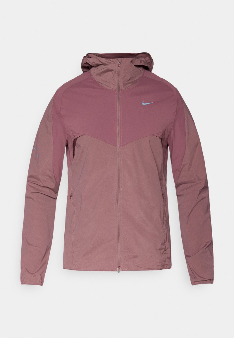 Leichte Nike-Jacke in gedämpftem Mauve mit Reißverschluss vorne, Kapuze und blauen Logo-Akzenten. Texturiertes Gewebe mit sportlichem Design.