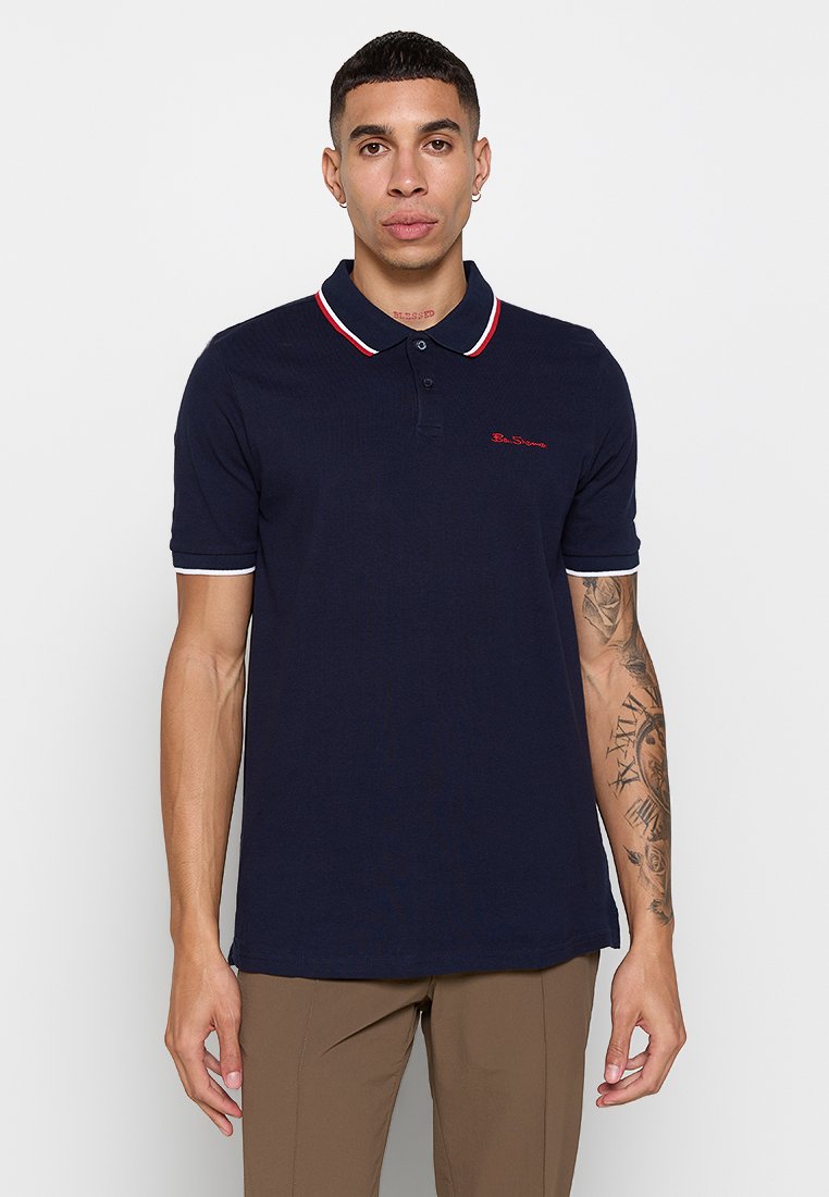 Navy Poloshirt aus strukturiertem Material, mit einem rot-weißen gestreiften Kragen und Ärmeln, Logo auf der Brust gestickt, kurze Ärmel.