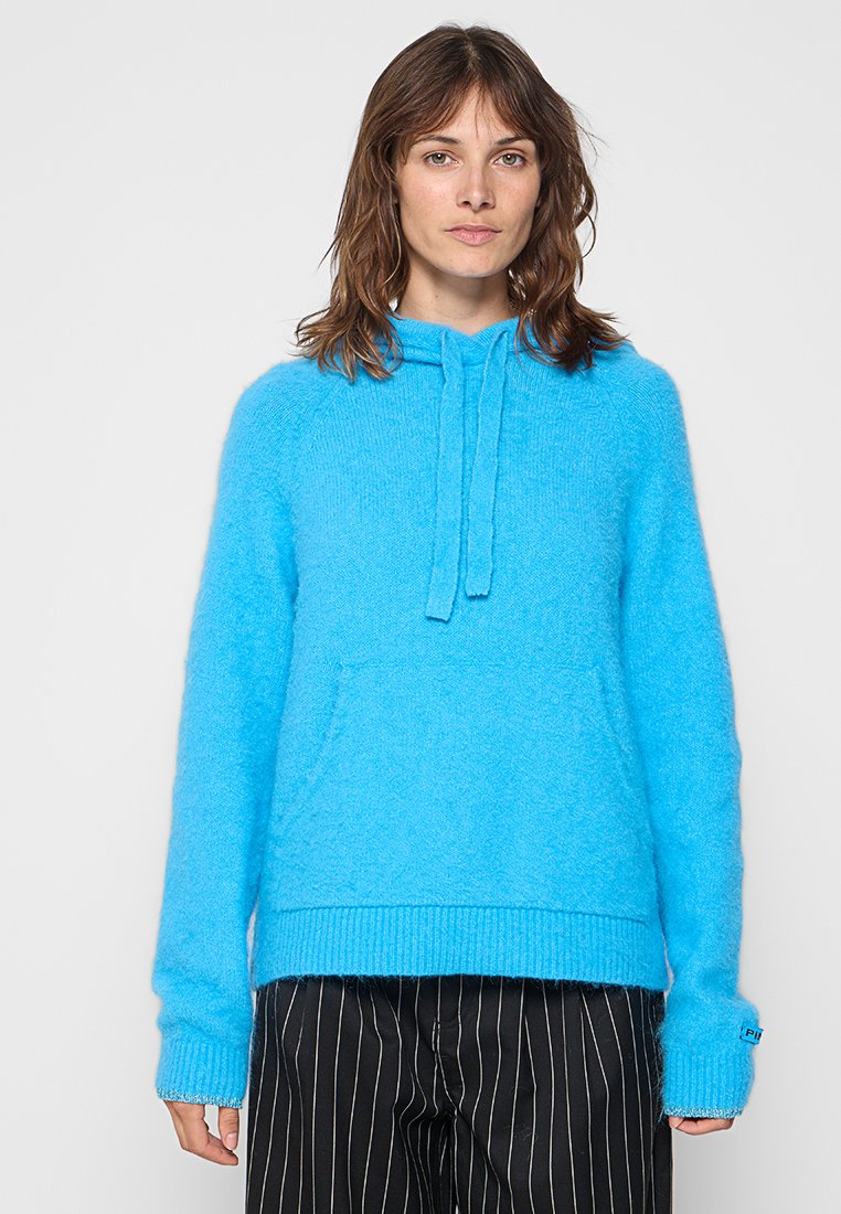 Blauer, flauschiger Hoodie mit einer Vordertasche, verstellbarem Kordelzug, gerippten Bündchen und Saum. Der Stoff wirkt weich und strukturiert.