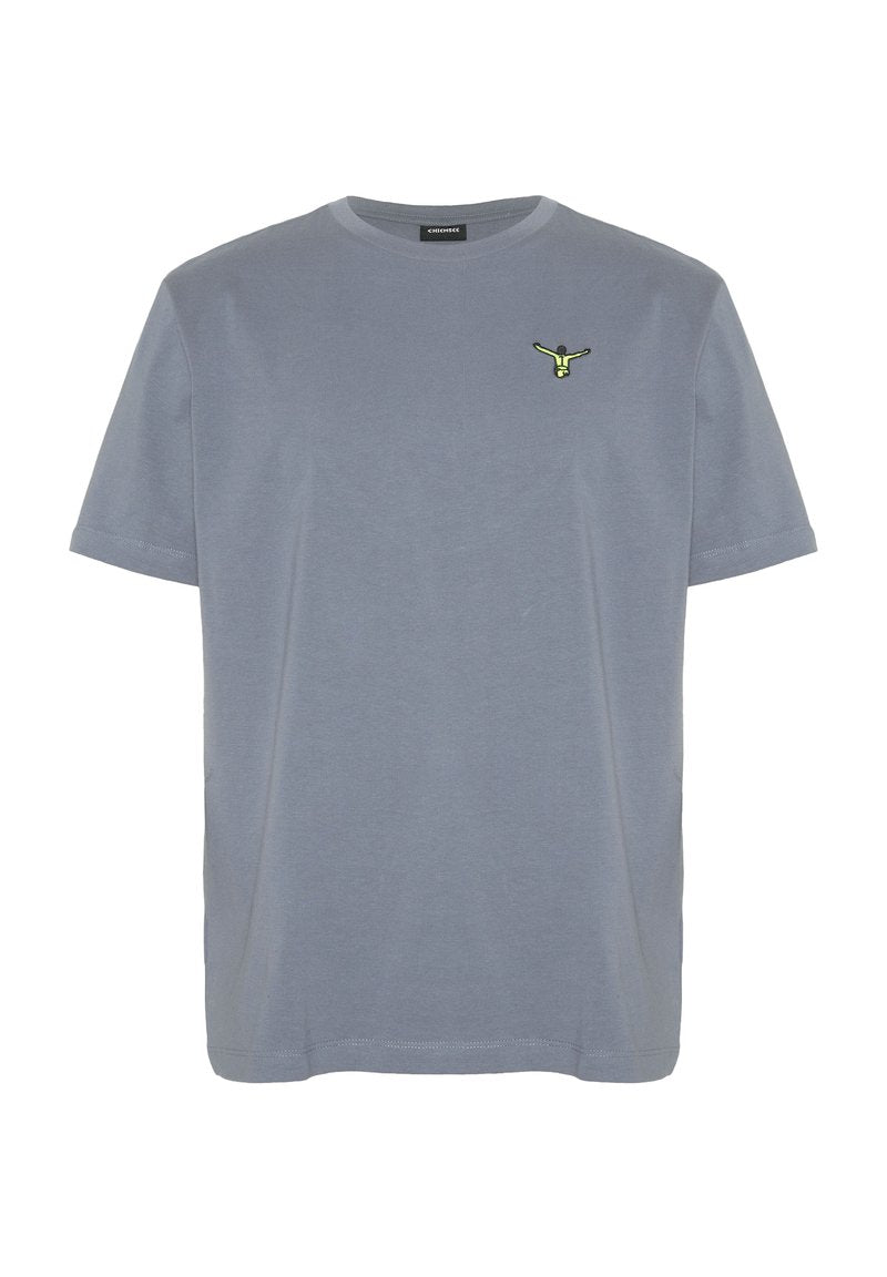Schlichtes graues T-Shirt mit kurzen Ärmeln und einem kleinen bestickten Motiv einer gelb-schwarzen Figur auf der linken Brust.