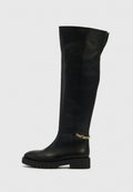 Schwarzer kniehoher Lederstiefel mit flacher Sohle, runder Zehenpartie und goldener Kettenverzierung am Knöchel. Glatte Textur mit minimaler Nahtführung.