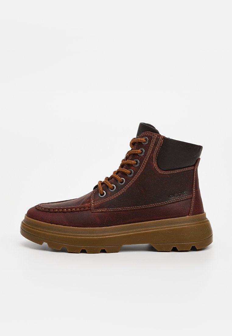 Braune Leder-Stiefeletten mit dunklen braunen Akzenten, runder Zehenpartie, gepolstertem Schaft, dicker Gummi-Sohle und kontrastierenden Nähdetails.