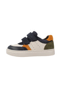 Niedrig geschnittener Sneaker mit marineblauen Klettverschlüssen, weißen Lederseiten, orangefarbenen und olivgrünen Wildlederelementen sowie einer dicken weißen Sohle.