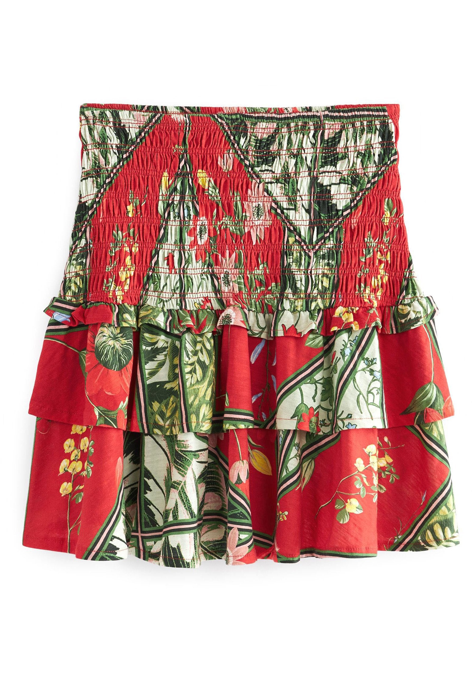 Roter Rock mit floralem Print und Lagenlook, mit gerafftem Oberteil. Verfügt über grüne und weiße Akzente, Rüschen und einen strukturierten Stoff.