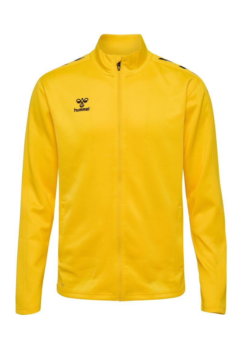Gelbe Sportjacke mit hohem Kragen, durchgehendem Reißverschluss, seitlichen Taschen und schwarzem Logo; aus glattem, leichtem Stoff mit einer taillierten Passform hergestellt.