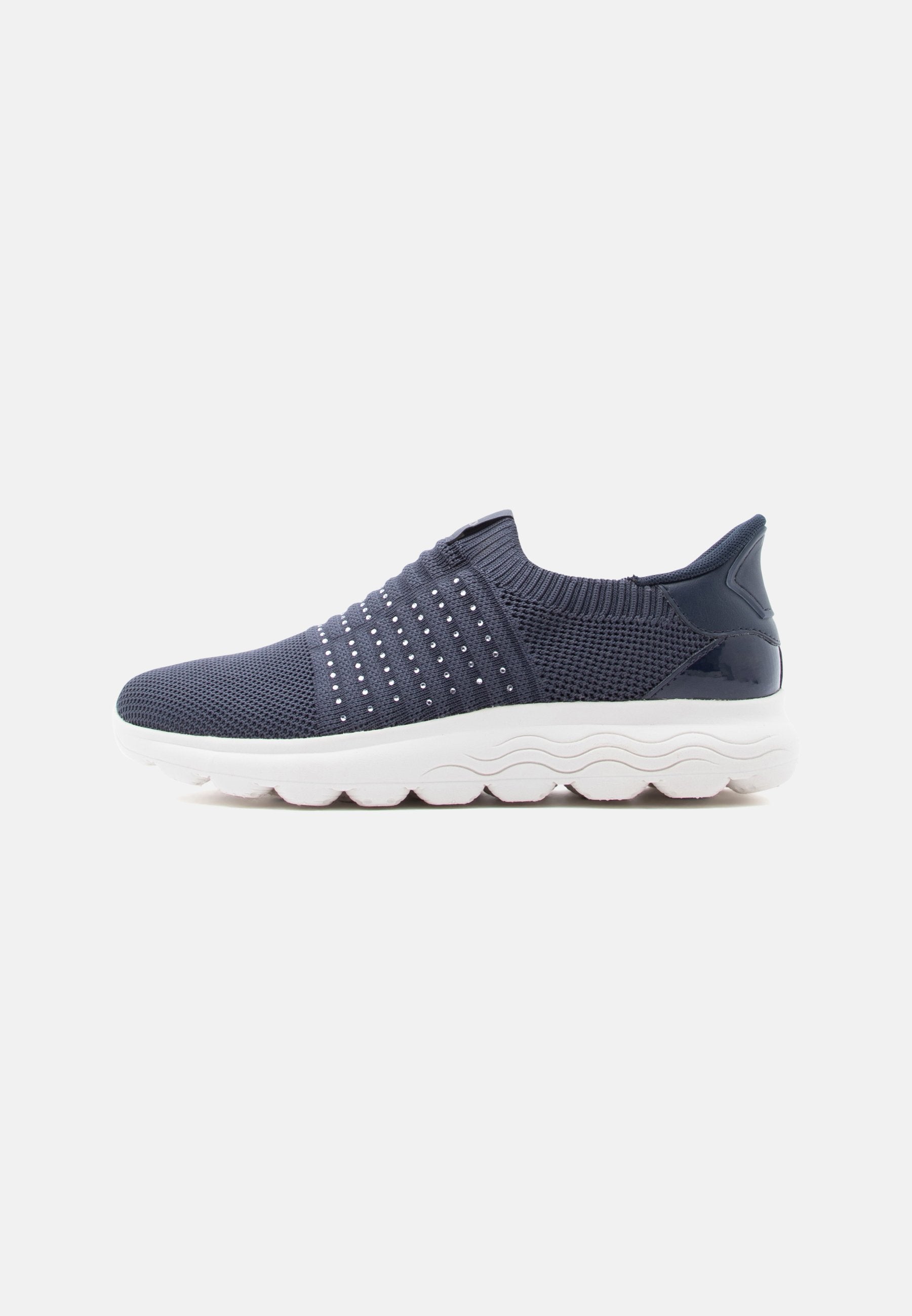Marineblaue Slip-On-Sneaker mit einem Mesh-Obermaterial, verziert mit dekorativen metallischen Punkten und einer gepolsterten weißen Sohle mit Wellenmuster.