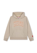 Beige Baumwollkapuzenpullover mit Kängurutasche, auf der Vorderseite mit dem Schriftzug "HUGO" in orangefarbener Umrandung und einem roten Markenschild am Ärmel.