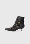 Schwarze Lederstiefelette mit spitzem Zehenbereich, ausgestattet mit goldenen und silbernen Hardware-Akzenten, verstellbaren Riemen und einem moderaten Absatz.