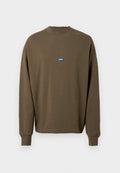 Braunes Sweatshirt mit langen Ärmeln, Rippstrickbund am Kragen und an den Ärmelabschlüssen. Auf der Brust befindet sich ein blaues rechteckiges Logo-Patch. Weiches Baumwollmaterial.