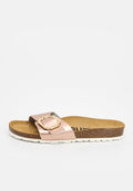 Pantoletten mit Korksohle, weißer strukturierter Außensohle und einem metallic-roségoldfarbenen Riemen mit einer großen geometrischen Schnalle.