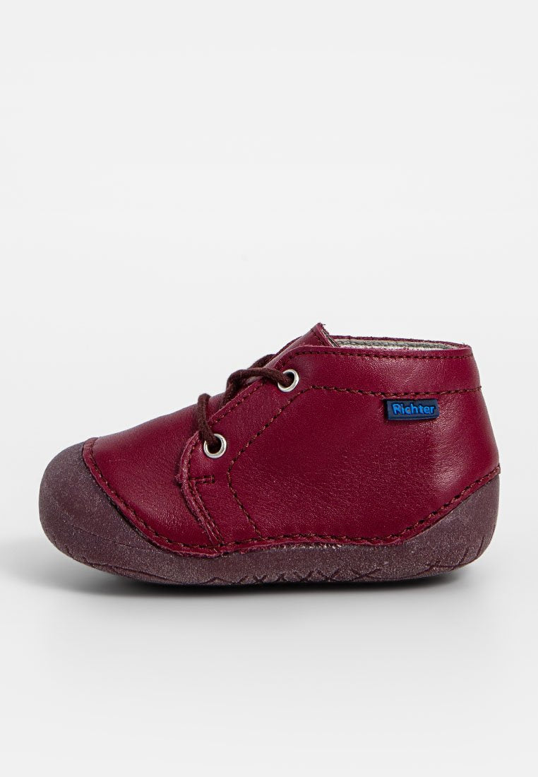 Burgunderfarbene Lederschuhe für Kinder mit braunen Gummisohlen, runder Spitze und Schnürdesign. Mit einem kleinen blauen "Richter"-Logo.