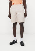 Mann trägt beige gestrickte Shorts, schwarze Loafers, weiße Socken und ein oranges T-Shirt mit einem teilweisen Karottengrafik.