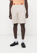 Mann trägt beige gestrickte Shorts, schwarze Loafers, weiße Socken und ein oranges T-Shirt mit einem teilweisen Karottengrafik.