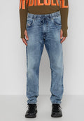 Mann trägt hellblaue Jeans-Jogginghosen mit Kordelzug und schwarze Sneakers, steht vor einem weißen Hintergrund.