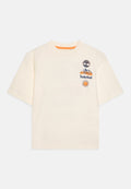 Cremfarbener T-Shirt mit kurzen Ärmeln, das mit gestickten Mustern verziert ist: einem Baum, Bergen mit "Timberland" und einer Sonne. Rundhalsausschnitt. Weiches Baumwollmaterial.