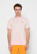 Mann trägt hellrosa kurzärmeliges Sportshirt und leuchtend orangefarbene Shorts und steht vor einem schlichten weißen Hintergrund.