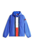 Blauer Windbreaker mit Kapuze, mit weißen, roten und marineblauen vertikalen Streifen in der Mitte und einem kleinen Flaggenpatch am linken Ärmel.