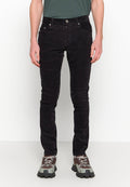 Schwarze Cordjeans im Slim-Fit, mit fünf Taschen, Nähtelementen und einem Reißverschluss. Kombiniert mit grauen und braunen Sneakers.