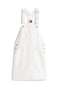 Weißes Latzkleid mit verstellbaren, überkreuzten Trägern am Rücken, Brusttasche vorne, Knopfdetails an den Seiten und Tommy Jeans Logoaufnäher.