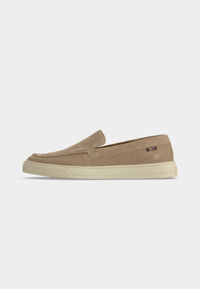 Beiger Veloursleder-Slipper mit weißer Gummisohle und kleinem mehrfarbigem Stoffetikett an der Fersenseite.