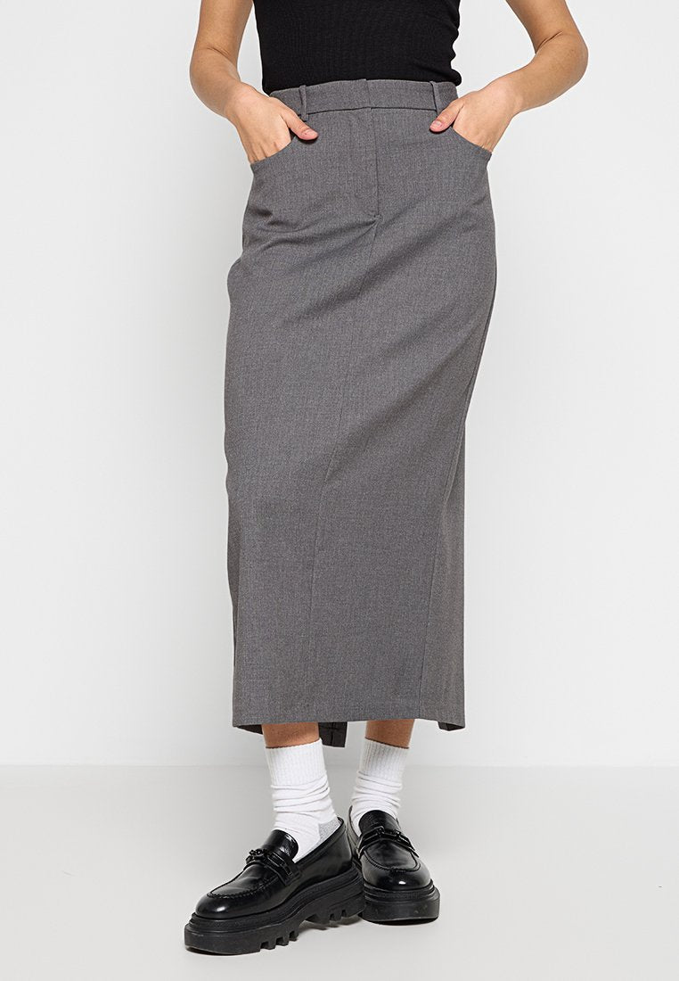 Grauer maßgeschneiderter Midirock mit hoher Taille, seitlichen Taschen und gerader Silhouette. Tragen mit schwarzen Schuhen und weißen Socken.