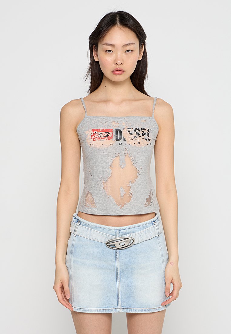 Graues Tanktop mit Ausschnitten und einem aufgedruckten "DIESEL"-Logo. Kombiniert mit einem hellblauen Jeans-Minirock mit einer runden Schnalle.