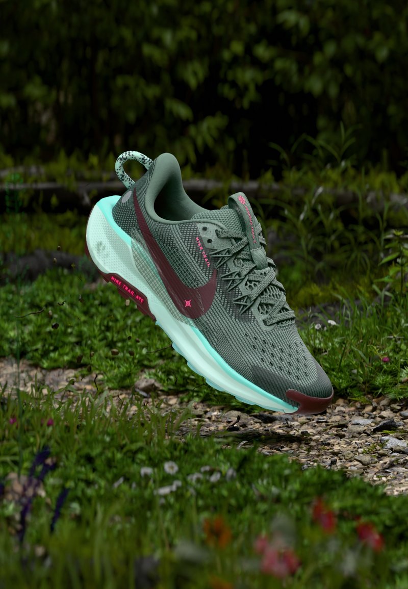 Nike-Laufschuh mit einem grünen Mesh-Obermaterial, braunen Akzenten, türkisfarbenen Sohlen und strukturierten Details. Ausgestattet mit einem Schnürsystem und einer Fersenschlaufe.