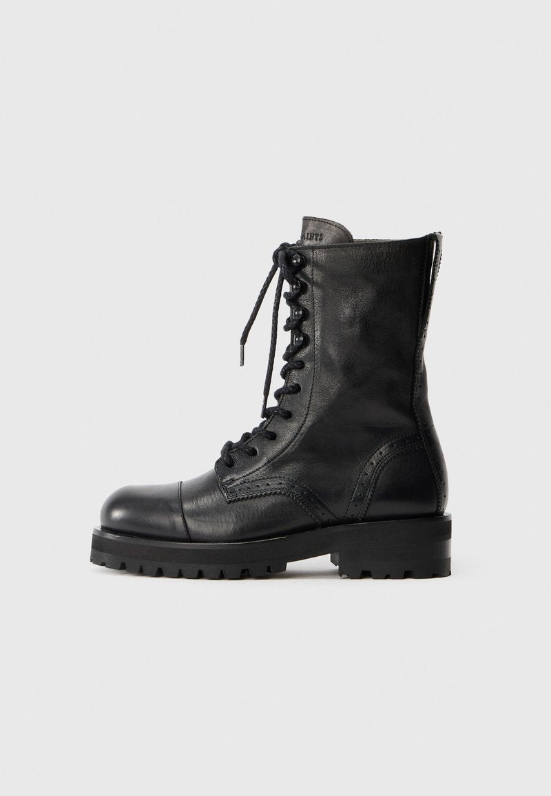 Schwarze Leder Schnürstiefel mit runder Zehenpartie, Broguemuster und robuster Gummisohle. Verfügt über einen Reißverschluss auf der Rückseite für ein einfaches An- und Ausziehen.