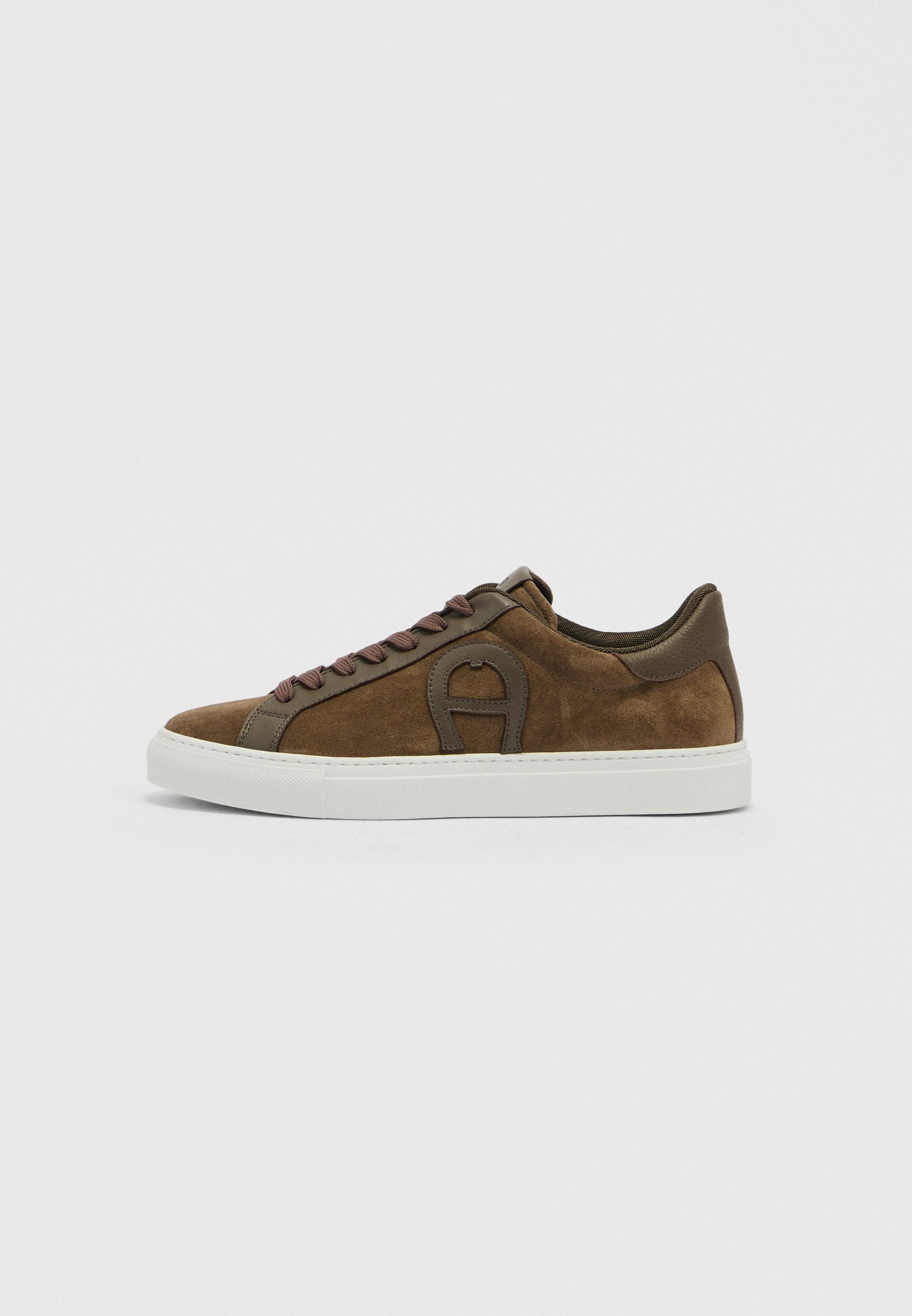 Brauner Low-Top-Sneaker aus Wildleder mit dunkelbraunen Lederakzenten, passenden Schnürsenkeln und weißer Gummisohle vor weißem Hintergrund.
