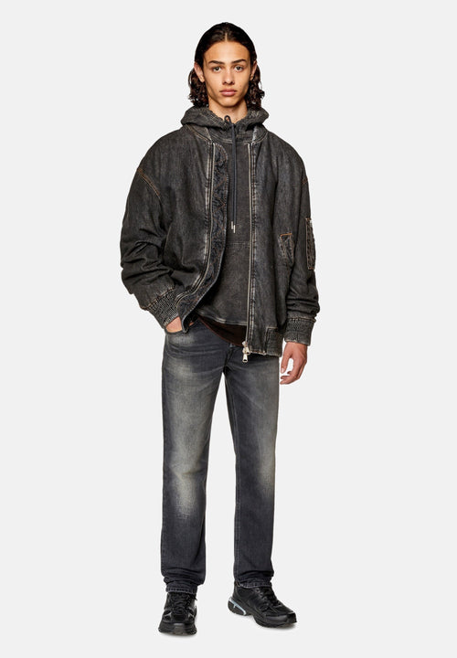 Dunkelgraue Jeansjacke mit sichtbaren Nähten, über einem grauen Hoodie getragen. Kombiniert mit hellgrauen Jeans und schwarzen Sneakers.
