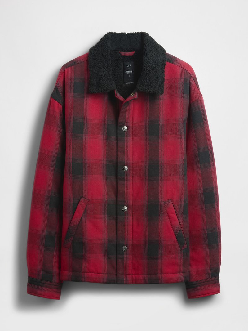Rote und schwarze kariertes Jacke mit einem schwarzen Kunstpelzkragen, Druckknöpfen und seitlichen Taschen. Das Material wirkt robust mit einer strukturierten Oberfläche.