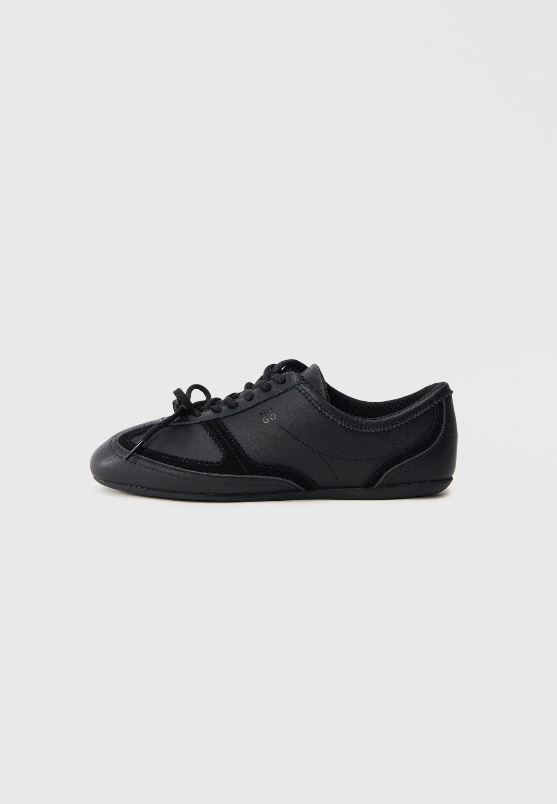 Schwarzer Sneaker mit niedrigem Profil, Schnürung, glatter und glänzender Oberfläche, minimalen Nähten und flacher Sohle auf schlichtem Hintergrund.