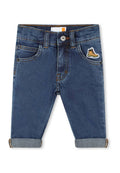 Dunkelblaue Jeans mit eng anliegendem Schnitt, mit umgeschlagenen Säumen und einem Logo-Patch eines Stiefels auf der rechten Tasche.