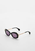 Schwarze Sonnenbrille mit ovalen lila Gläsern, verziert mit Perlenakzenten entlang der oberen Kante und goldfarbenen Metallbügeln mit strukturierten Details.