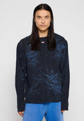 Schwarzes Langarmshirt mit einem distressed Design, das kleine Löcher und ein Batikmuster in Blautönen aufweist. Rundhalsausschnitt.