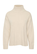 Cremfarbener Pullover mit hochgewalztem Kragen, überschnittenen Schultern und geripptem Saum. Der Stoff scheint weich und strukturiert zu sein.