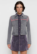 Graue Jeansjacke mit pinken Schulterakzenten. Verfügt über einen Kragen, eine Knopfleiste und eine taillierte Passform. Trägt man über einem lila Jeanskleid.