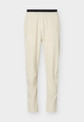 Beige Slim-Fit-Hose mit schwarzem elastischem Bund, aus leichtem, glattem Stoff, geeignet für Freizeit- oder Sportbekleidung.