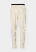 Beige Slim-Fit-Hose mit schwarzem elastischem Bund, aus leichtem, glattem Stoff, geeignet für Freizeit- oder Sportbekleidung.