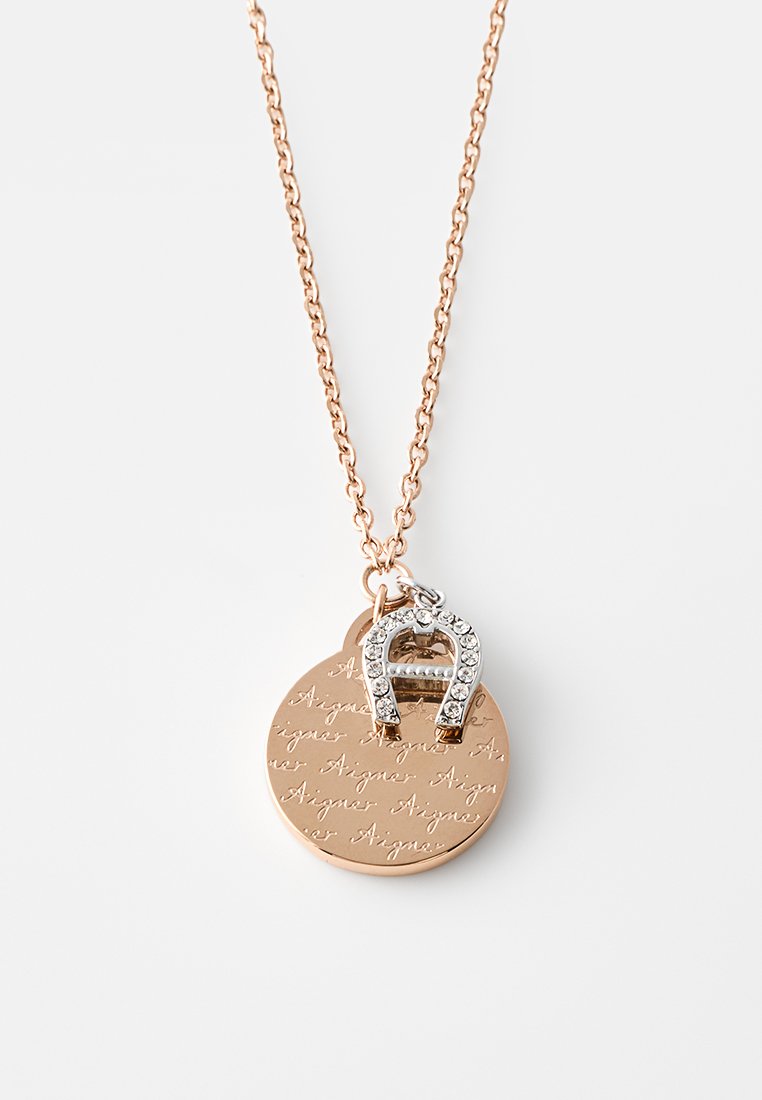 Kette aus Roségold mit zwei Anhängern: eine runde Scheibe mit eingraviertem Kursivtext und ein mit Strasssteinen besetztes Hufeisen-Anhänger.