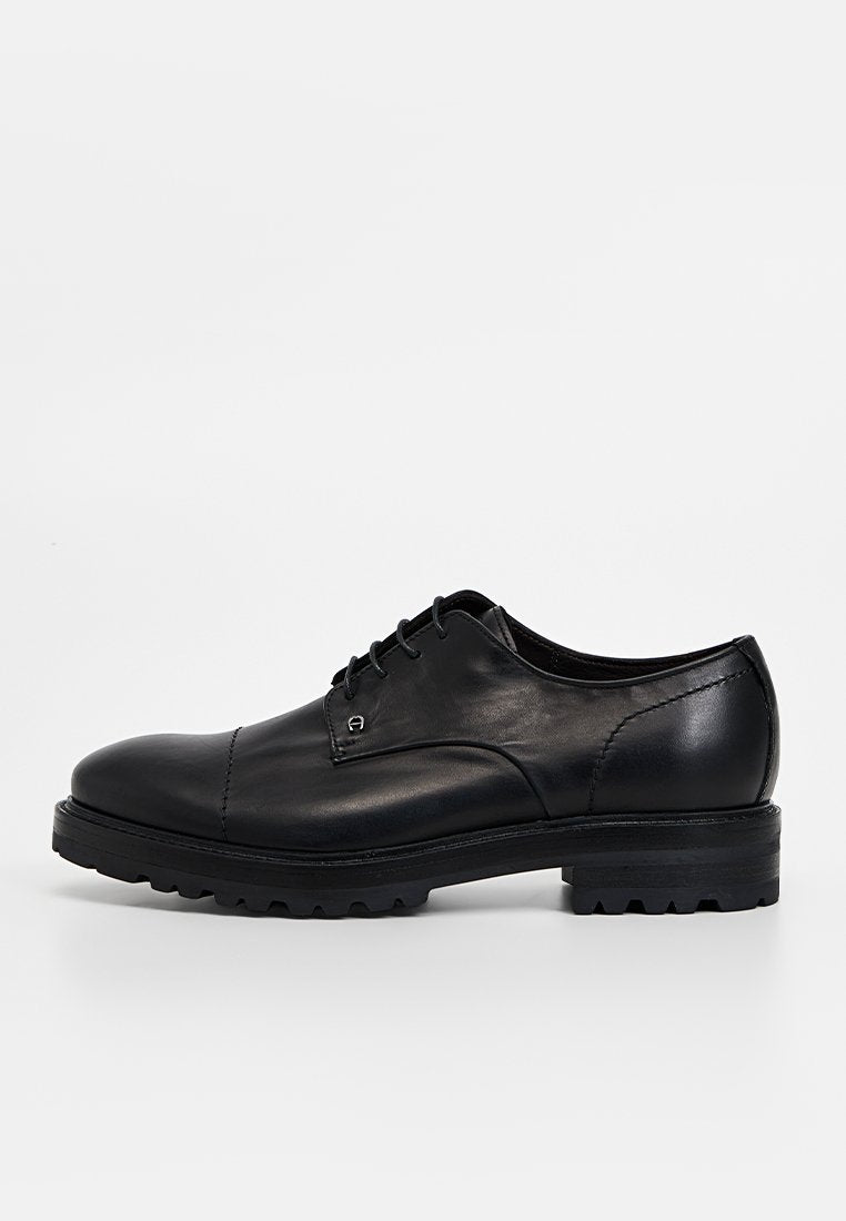Schwarze Schnürschuhe aus Leder mit abgerundeter Spitze, strukturierter Oberfläche und einer Gummisohle mit tiefem Profil für verbesserten Halt.