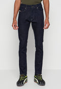 Dunkelblaue Jeans im Slim Fit mit fünf Taschen, design mit kontrastierenden Nähten. Kombiniert mit schwarzen und grünen Sportschuhen.