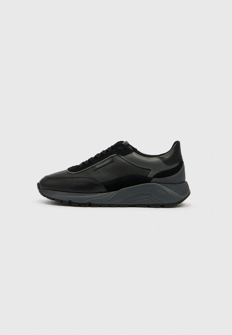 Schwarze Sneaker aus Leder mit grauen Akzenten, Schnürdesign, strukturierten Paneelen und einer klobigen Sohle mit wellenförmigem Muster. Logo an der Seite.