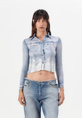 Gekürzte Denim-Bluse mit langen Ärmeln, hellblauer Waschung, Knopfleiste, zwei Brusttaschen und ausgefransten Saumdetails, kombiniert mit hellen Denim-Jeans.