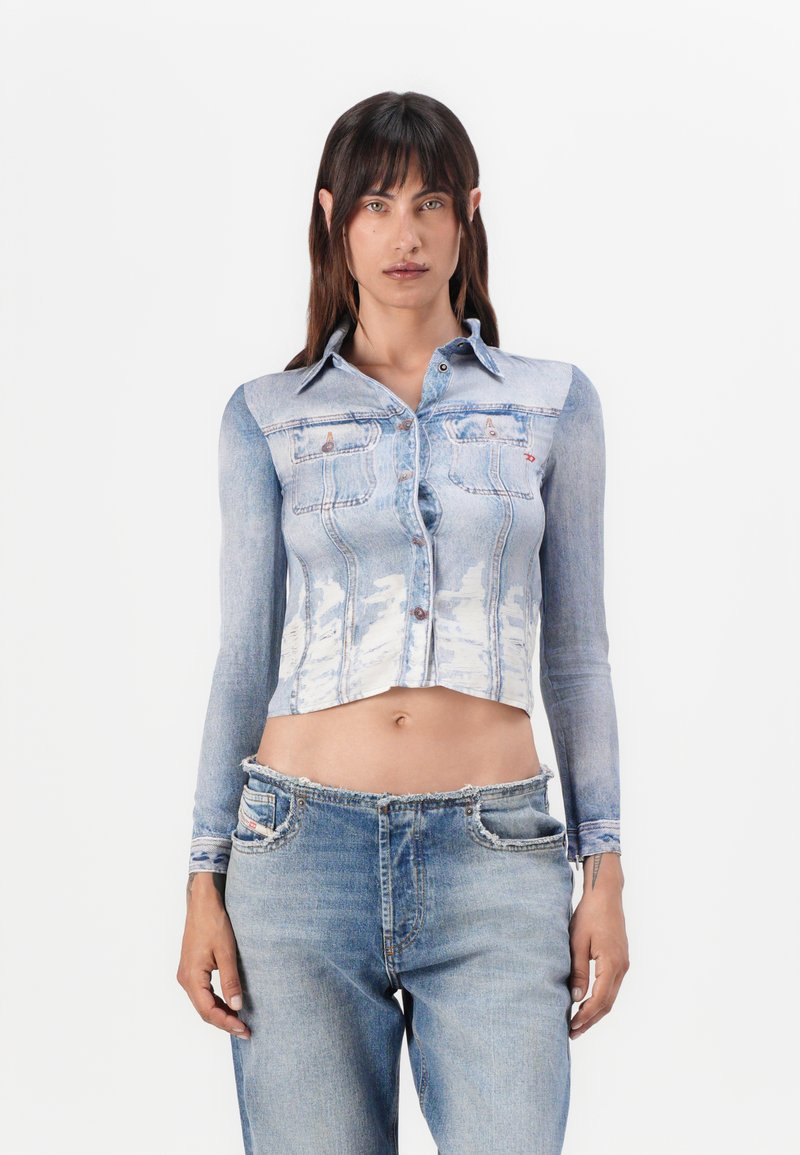Gekürzte Denim-Bluse mit langen Ärmeln, hellblauer Waschung, Knopfleiste, zwei Brusttaschen und ausgefransten Saumdetails, kombiniert mit hellen Denim-Jeans.