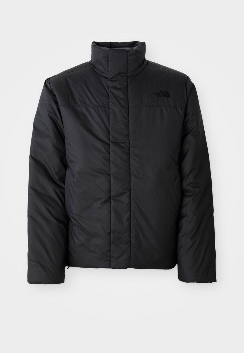 Schwarze isolierte Jacke mit hohem Kragen, ausgestattet mit einem durchgehenden Reißverschluss und einem Logo auf der linken Brust. Das Material wirkt glatt und plüschig.
